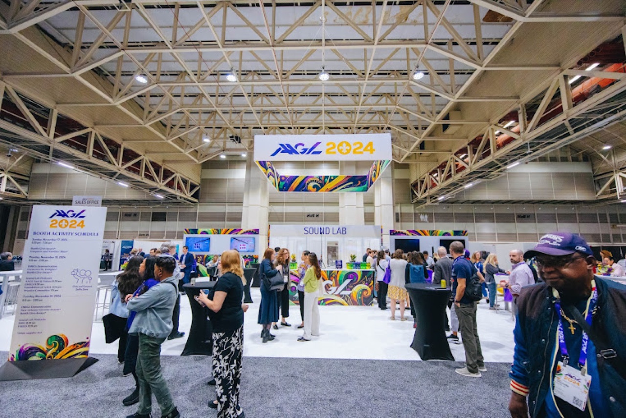 AAGL 2024 branded booth hub with hanging signage, Sound Lab, and attendees at exhibit hall